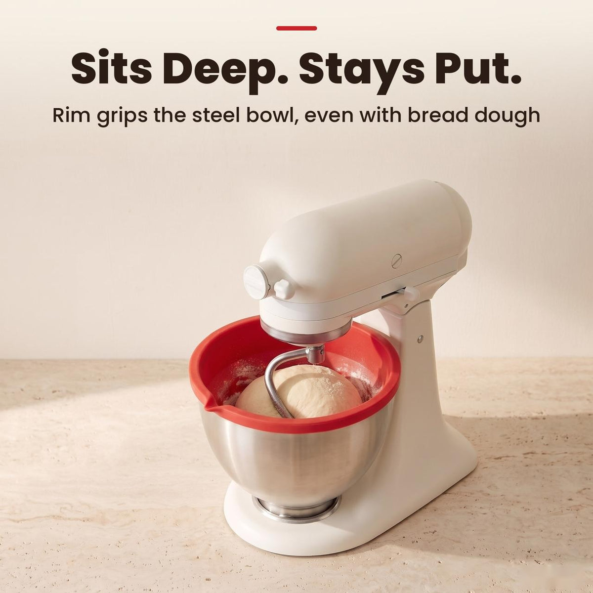 Red silicone liner inside a tilt-head stand mixer steel bowl kneading bread dough